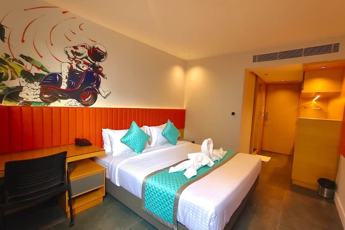 Habitación de hotel con dos camas, un escritorio, una silla, zona de ducha y un mural en la pared.