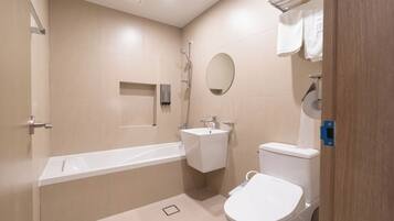 Un baño moderno con bañera, inodoro, lavabo y espejo.