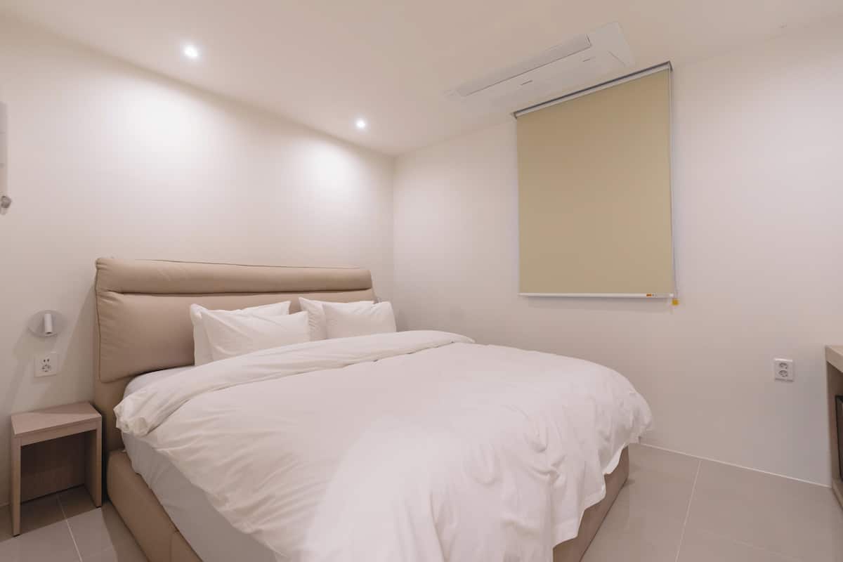 A bedroom with a bed, bedside table, and a wall-mounted air conditioner.