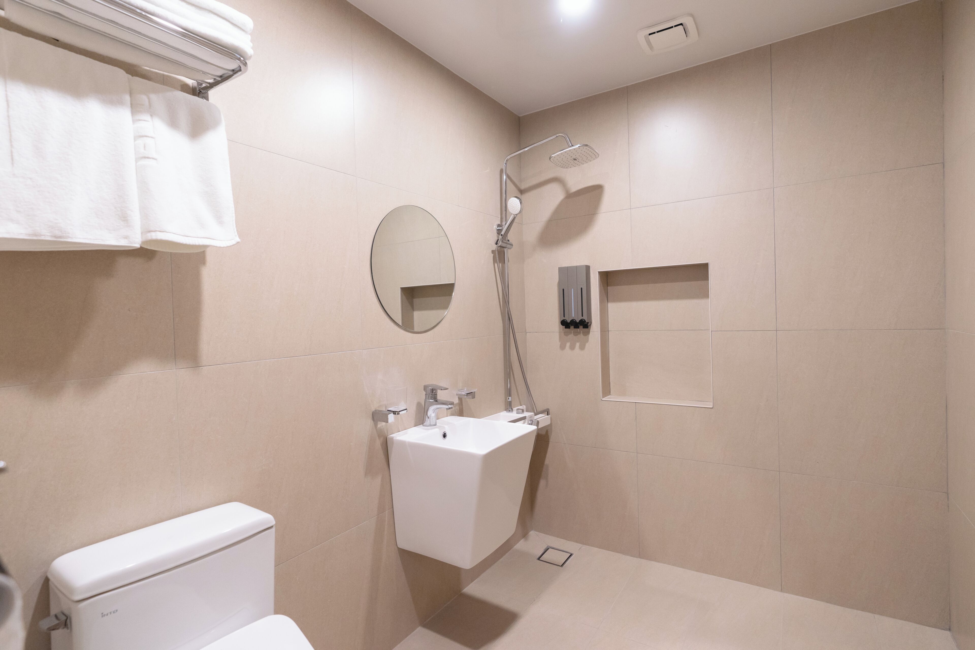 Un baño moderno con inodoro, lavabo, espejo y ducha.