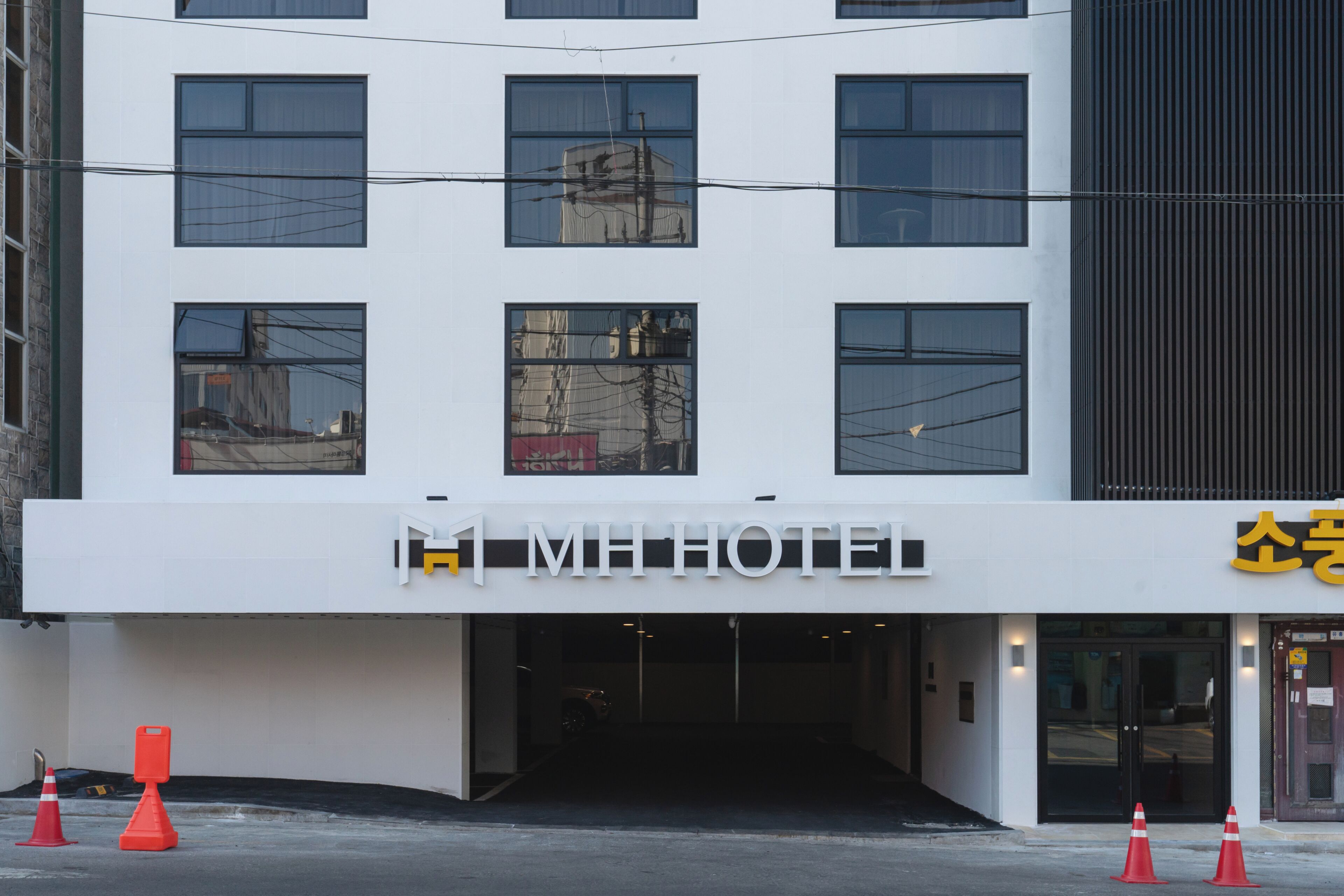 A modern hotel with a white facade, multiple windows, and a visible entrance.