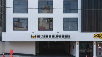 A modern hotel with a white facade, multiple windows, and a visible entrance.