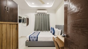 A bedroom with a bed, a desk, a wardrobe, a ceiling fan, and an air conditioning unit.