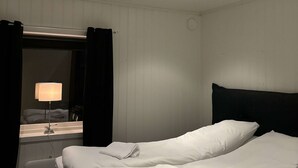 Quarto de hotel com cama, mesa de cabeceira, abajur e espelho.