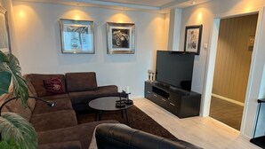Uma sala de estar moderna com um sofá seccional, uma mesa de centro, uma TV de tela plana e obras de arte nas paredes.