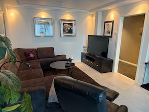 A modern living room with a sectional sofa, a coffee table, a flat-screen TV, and artwork on the walls. - Cityscape Retreat - Central and modern apartment (Tromsø)