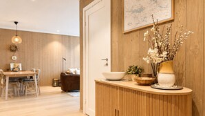 Un intérieur moderne avec un mur en bois, un coin repas comprenant une table et des chaises, un meuble contenant des objets décoratifs et une carte accrochée au mur.