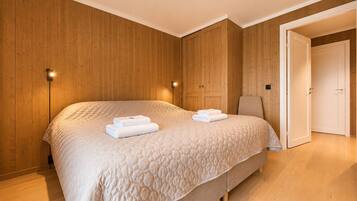 Un dormitorio con una cama grande, paredes de madera, una mesita de noche y una puerta.