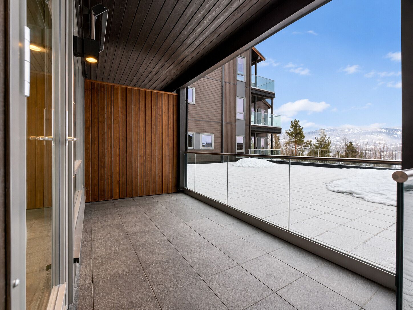A balcony with a view of a snowy landscape and a modern building.