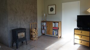 Un salon avec un poêle à bois, une bibliothèque, un téléviseur et une porte.