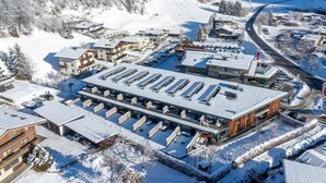 A snow-covered town with a large building featuring multiple balconies and a parking area. - Family Chalet Near Wildkogel Ski Slopes with Sauna (Neukirchen am Grossvenediger)