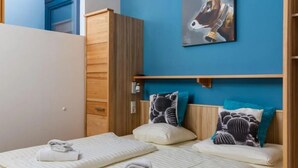 A bedroom with two beds, a wooden wardrobe, a blue wall, and a horse painting. - Family Chalet Near Wildkogel Ski Slopes with Sauna (Neukirchen am Grossvenediger)