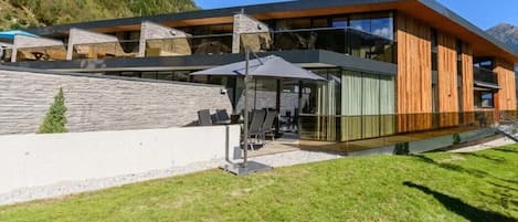 Un edificio moderno con fachada de vidrio, zona de estar al aire libre y pared de piedra.