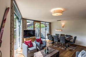 Un amplio salón con televisión, sofá, mesa de comedor y sillas.