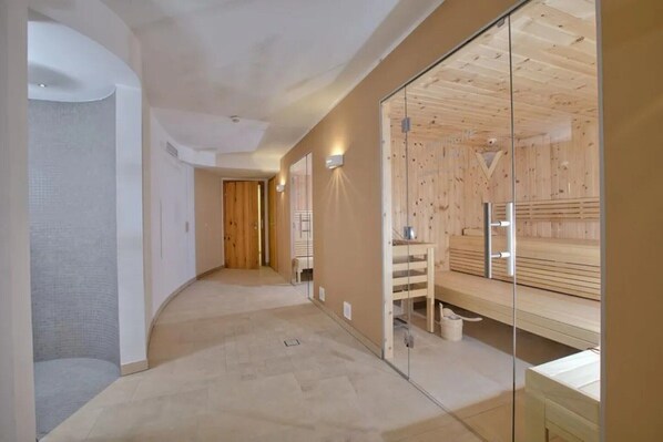 Un pasillo con zona de sauna, paredes de madera y un separador de vidrio.