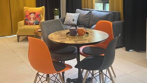 Una sala de estar moderna con un sofá, sillas, una mesa baja y una mesa de comedor.