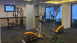 Un gimnasio con equipo de ejercicio, un espejo grande y una ventana con vistas a un edificio.