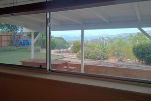 Überdachte Terrasse mit Blick auf einen Garten und eine entfernte Landschaft.