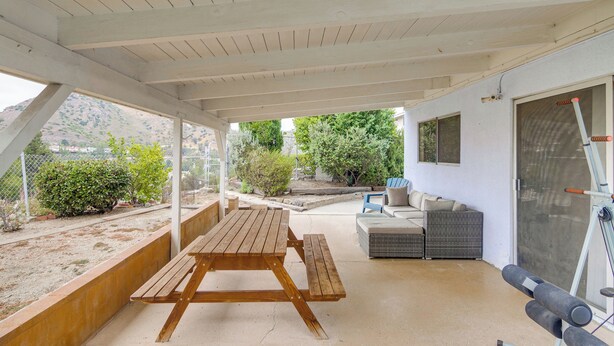 Eine Terrasse im Freien mit einem Holztisch und Bänken, einem Korbsessel und einem Laufband.
