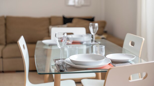 Una mesa de comedor preparada con platos, vasos y cubiertos.