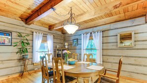 Un interior de madera con una mesa de comedor, sillas, una lámpara colgante y una planta en maceta.
