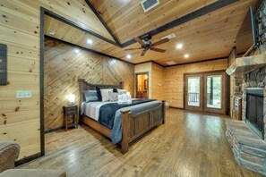 Ein Holzblockhaus-Innenraum mit Bett, Kamin und Steinwand.