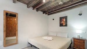 A bedroom with a bed, a wooden wardrobe, a nightstand, a lamp, and a painting on the wall. - Charming Farmhouse Retreat in Arona with Stunning Views (Arona)