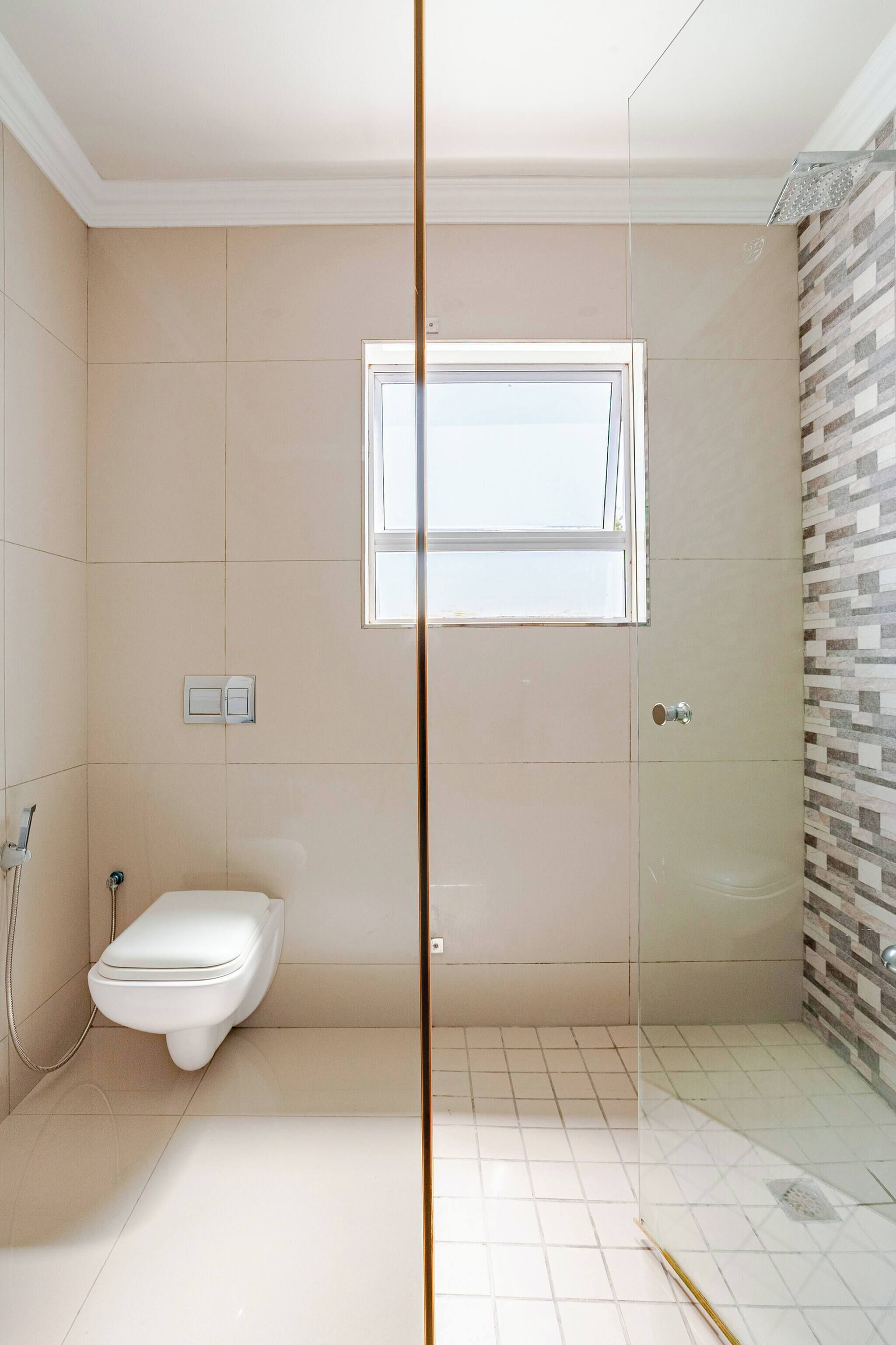 A bathroom with a toilet, a shower, and a window.