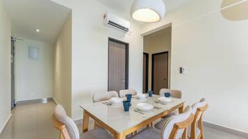 A dining area with a table set for four, chairs, an air conditioning unit, and a door.