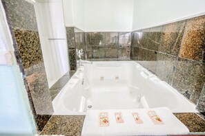 Un baño moderno con una bañera grande, baldosas de granito y una toalla con diseño floral.
