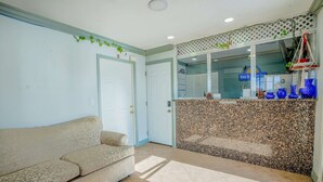 Un salon avec un canapé, un sol carrelé, une porte et une fenêtre agrémentée d’objets décoratifs.