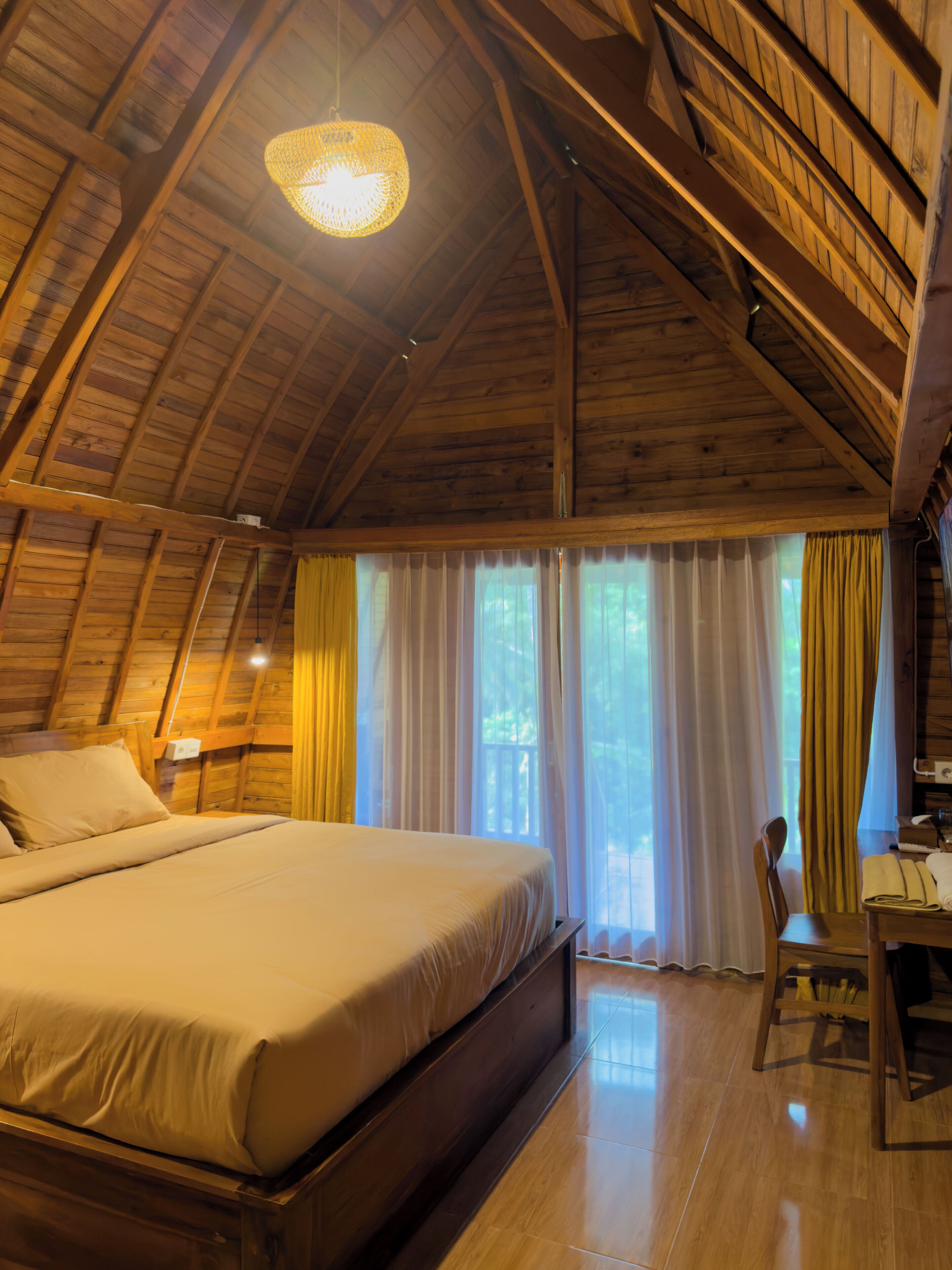 Une pièce avec un plafond en bois, un lit, un bureau et une chaise.