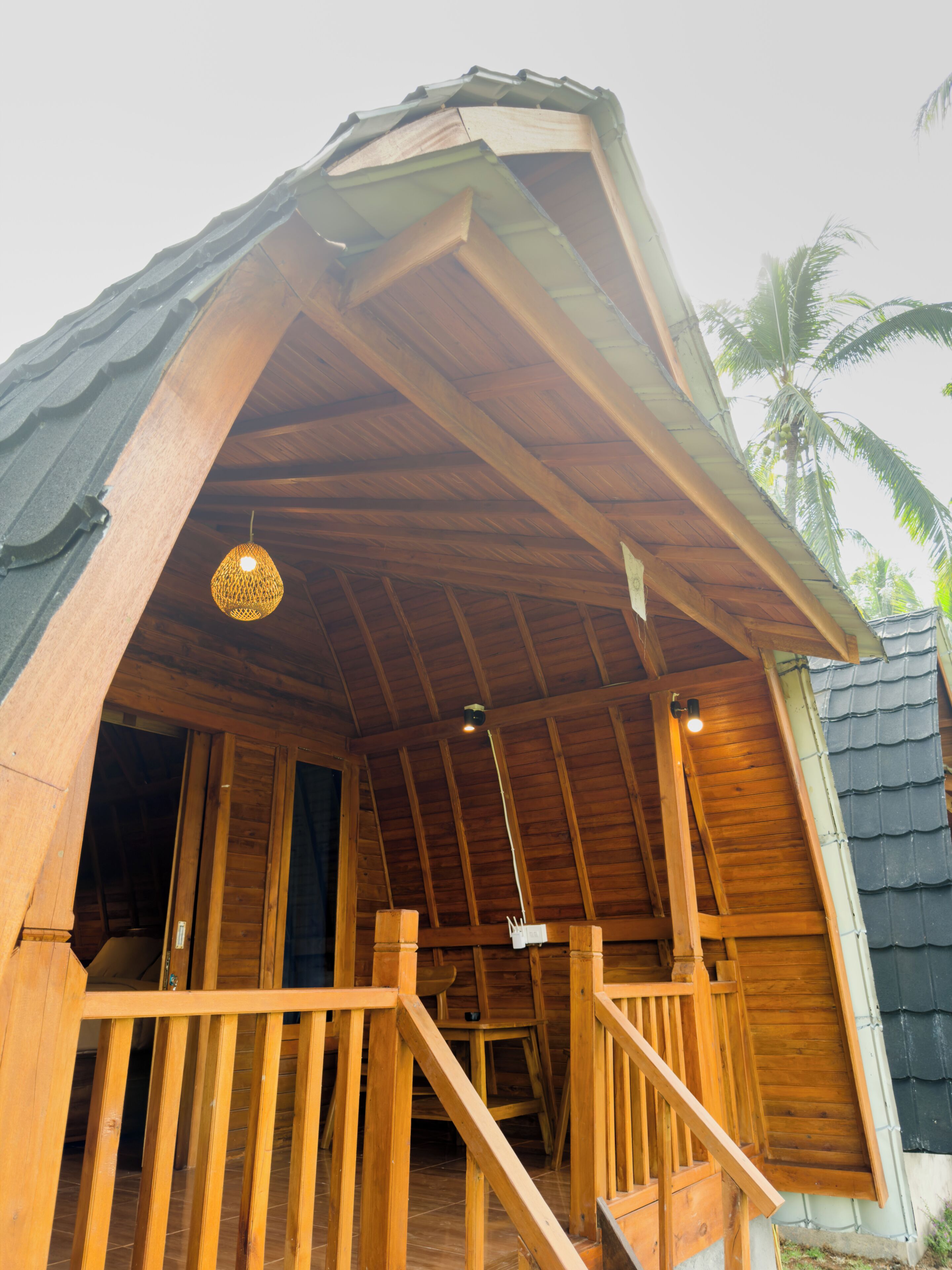 A wooden structure with a sloped roof, a staircase leading to an upper level, and a hanging light fixture.