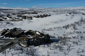 A snow-covered ski resort with multiple buildings, including a large lodge with a ski lift visible.