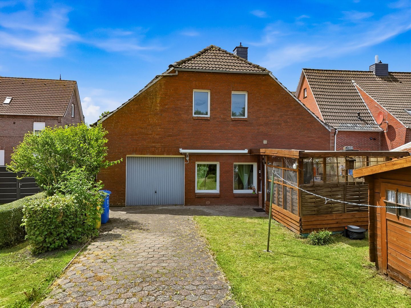 A brick house with a paved driveway, a garage, and a wooden fence.