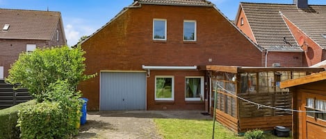 Une maison en briques avec une allée pavée, un garage et une clôture en bois.