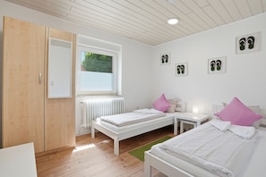 Un dormitorio con dos camas, un radiador, una ventana y un armario.