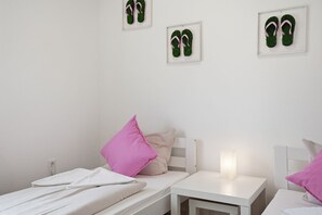 Ein Schlafzimmer mit einem Bett, zwei Nachttischen, einem Wandbild von Flip-Flops.