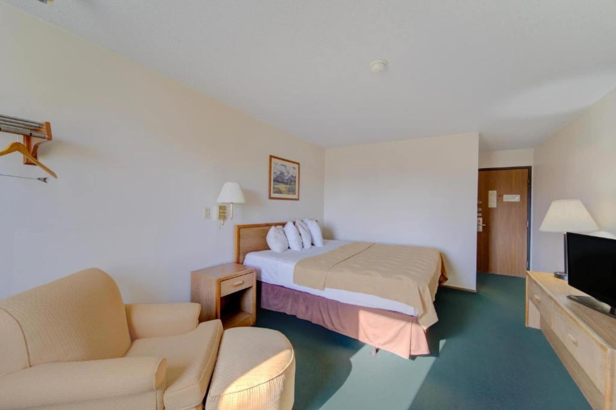 A hotel room with a bed, a television, a desk, a chair, and a nightstand.