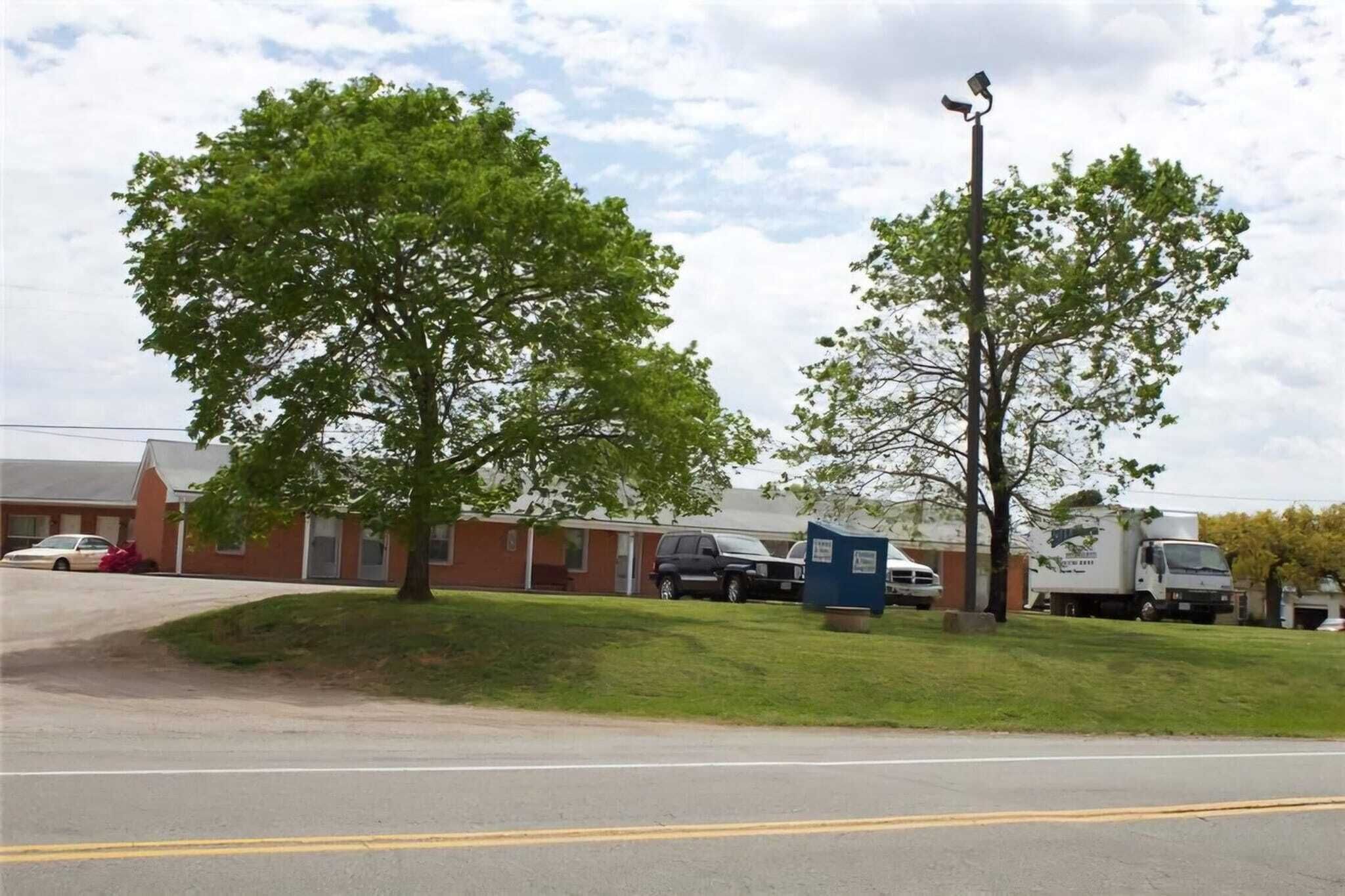 A building with a parking lot, a few trees, and a streetlight.