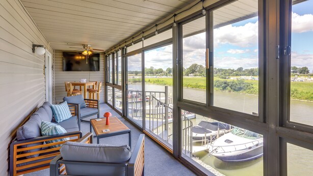 Een overdekt terras met uitzicht op een rivier en boten.