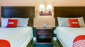 A hotel room with two beds, each with a pillow labeled 'OYO,' a nightstand with a lamp, and a small table with a phone. - Myrtle Beach SC | 3 full bed (Myrtle Beach SC)