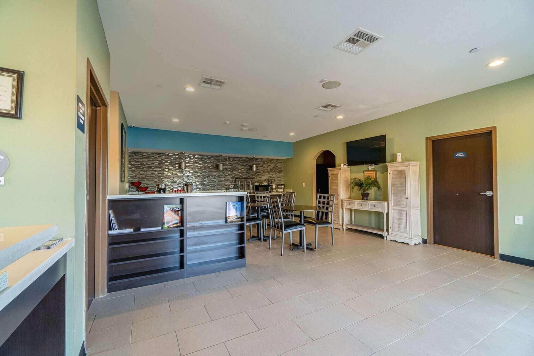 A spacious room with a kitchen area, a dining table, and a reception desk.