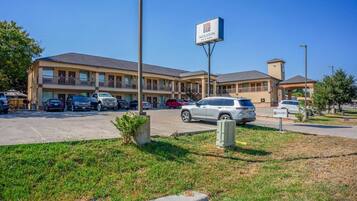 A motel with a signboard, multiple parking spaces, and a grassy area in front.