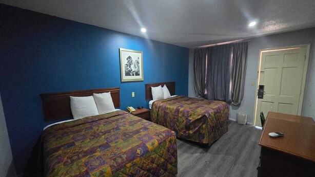 A hotel room with two beds, a desk, a telephone, and a door. - 2 Queen Beds Non-Smoking (Prentiss, MS)