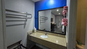 A bathroom with a sink, mirror, towel rack, and a blue accent wall. - King Bed Non-Smoking (Prentiss, MS)