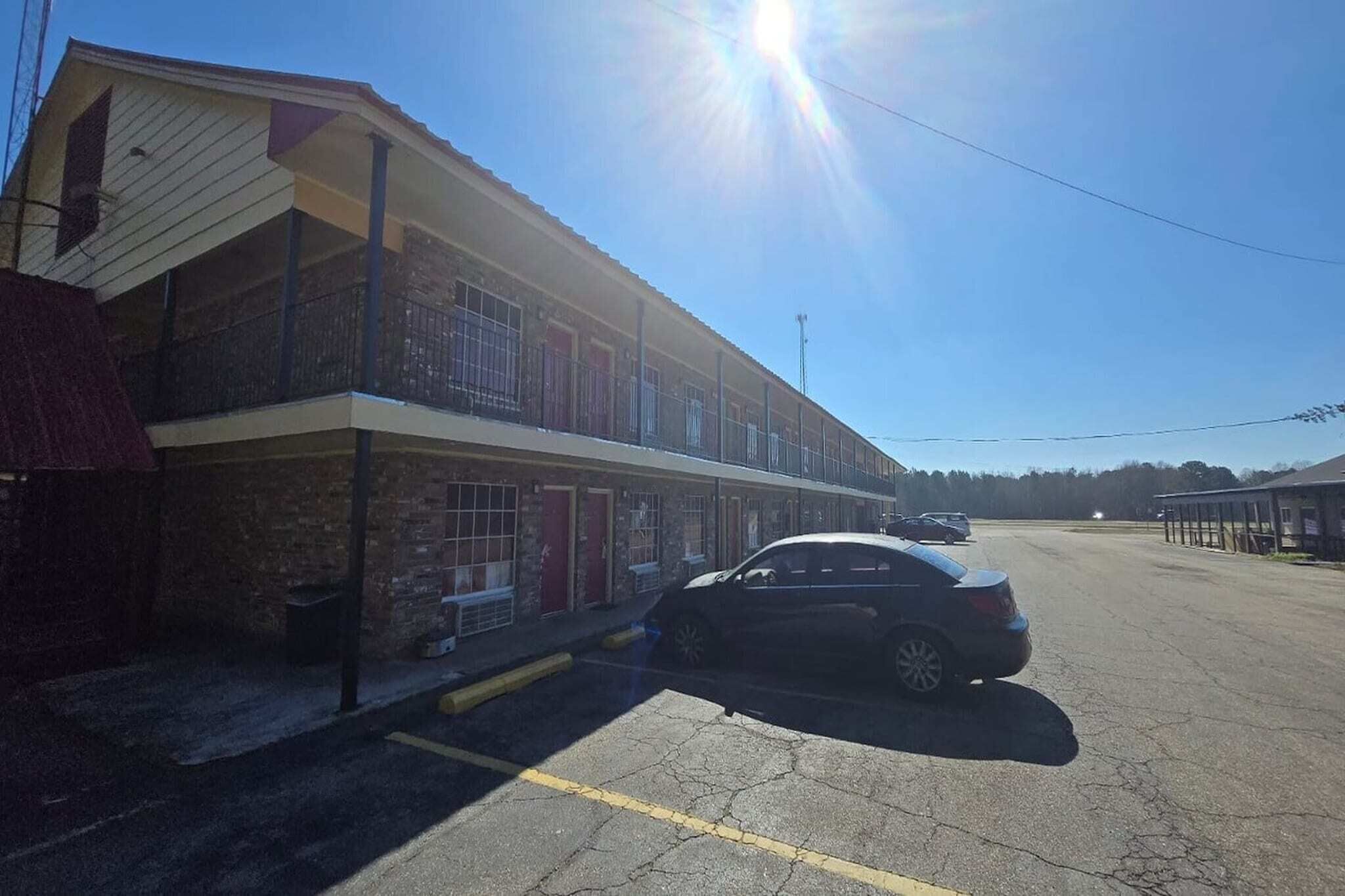 A two-story motel with a parking lot and a single-story building adjacent to it.