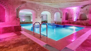 En swimmingpool med välvda ingångar, stenmurar och ett kaklat golv.