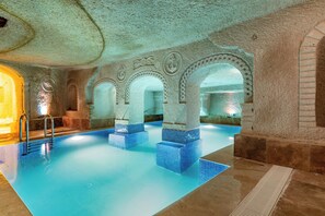 Ein Innenpool mit Steinbögen und blautonierten Stufen.