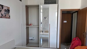 Una habitación con una cama, un armario, un espejo y una puerta.
